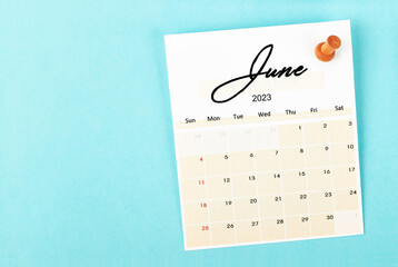The June 2023 and wooden push pin on blue background.