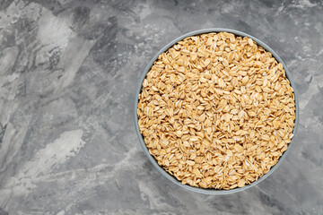 Dry oat flakes in bowl on a gray background. Oat groats flattened into flakes. Top view. Copy space