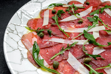 Meat carpaccio with cheese and arugula. flowers