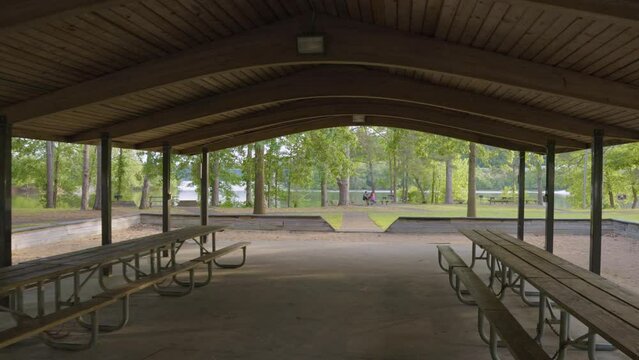 footage of a gorgeous spring landscape at Proctor Landing Park at sunset with rippling water surrounded by lush green trees and plants and a pergola with benches at Lake Acworth in Acworth Georgia USA