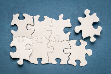 top view of white blank unfinished jigsaw puzzle on blue background, completing a task or solving a problem concept