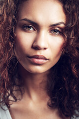 Beauty, closeup and portrait of woman in studio confident, beautiful and gorgeous on gray background. Salon, facial glow and face of female person with natural makeup, cosmetics and curly hairstyle