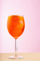 Glass of Aperol Spritz cocktail on a pink beige background. Cocktail Aperol Spritz with orange and ice cubes. Summer refreshing drink concept