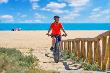 beautiful senior woman with her electric mountain bike at the golden sand beach of Isla Christina, Andalusia, Spain
