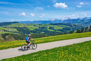 senior woman mountain biking on a electric mountainbike in early spring, in the Allgaeu Area,...