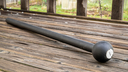 steel mace (or macebell) on a wooden deck, fitness concept using unconventional equipment, springtime scenery