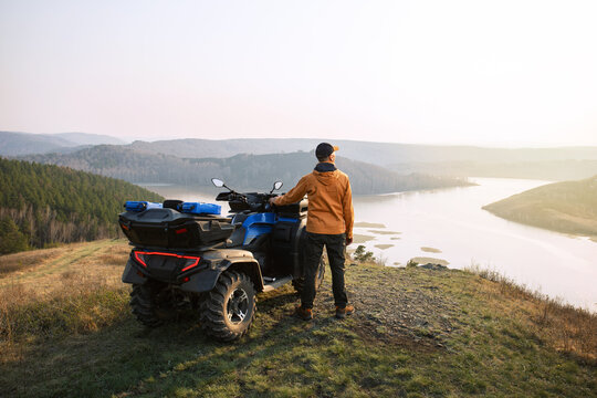 Back view of man traveler  on a quad bike in the mountains at sunset.  concept adventure summer vacations outdoor.