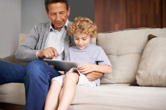 Tablet, child or grandfather typing on online to search for games on internet in retirement at home to relax. Grandparent or young kid enjoying watching videos with a senior or mature old man on sofa