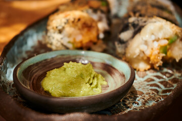 A colourful ceramic plate of freshly prepared, healthy sushi accompanied by a dash of wasabi for an authentic Japanese cuisine experience.