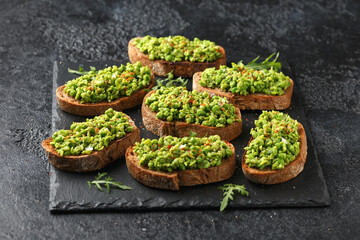 Mashed peas sourdough bread toast with sea salt flakes and chilli served on black slate