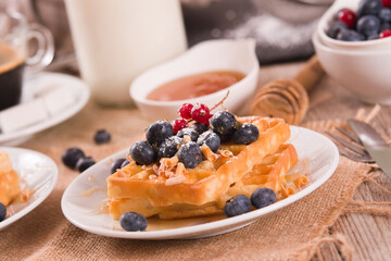 Waffles with red currant and blueberries on white dish. - 602332358