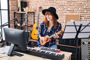 Fototapeta na wymiar Young woman musician singing song playing ukelele at music studio