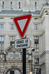 Paris, France - 16 April 2023:  Road yield sign with the building of the Paris Opera Garnier in the background