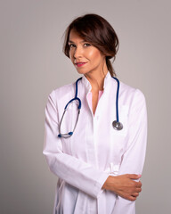 Female doctor wearing lab coat and stethoscope around her neck and standing at isolated background