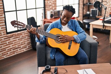 African american woman musician playing classical guitar at music studio