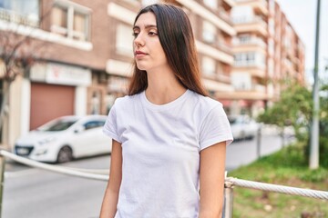 Young beautiful hispanic woman looking to the side with serious expression at street