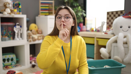 Young blonde woman preschool teacher asking for silence at kindergarten