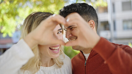 Man and woman couple smiling confident doing heart gesture with hands at park