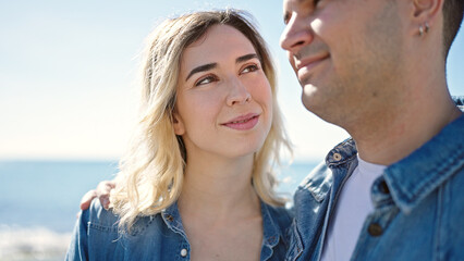 Man and woman couple smiling confident hugging each other at seaside