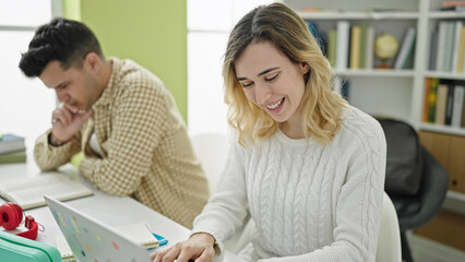 Man and woman students using laptop writing notes at library university