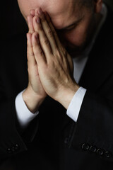 Fototapeta na wymiar Vertical image of mature man in black suit praying with his eyes closed