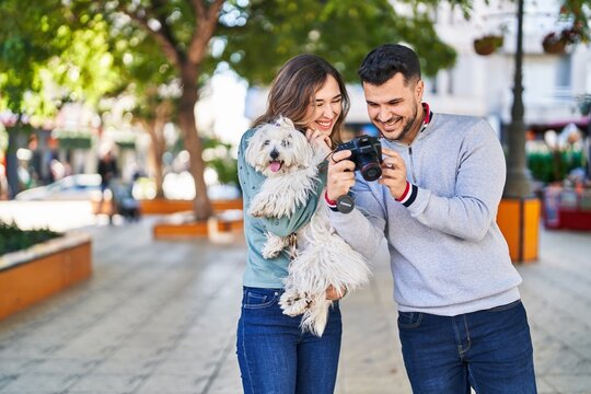 Man and woman holding dog using professional camera at park