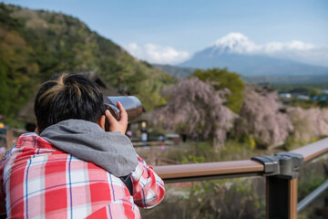 Fototapeta na wymiar Boy using telescope to see closeup mount Fuji and cherry tree