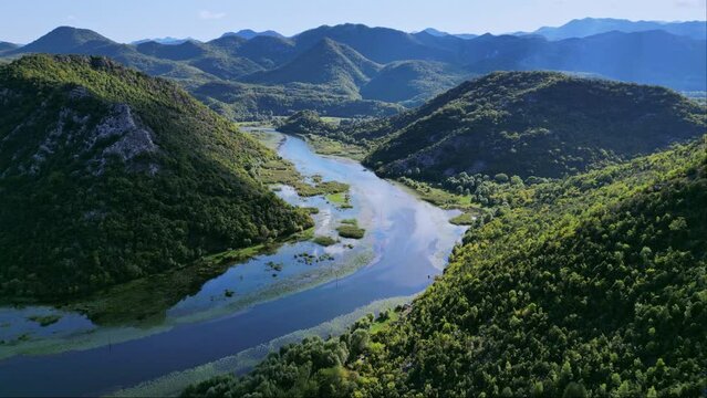 Drone flight over the bend of the Rijeka Crnojevica river near Lake Skadar while fishing from a moving boat. River between the mountains in Montenegro. 4K epic drone footage, montenegro mountains, 