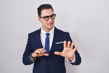 Young hispanic man wearing suit and tie disgusted expression, displeased and fearful doing disgust...