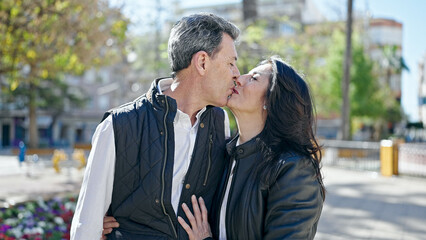 Senior man and woman couple standing together kissing at park