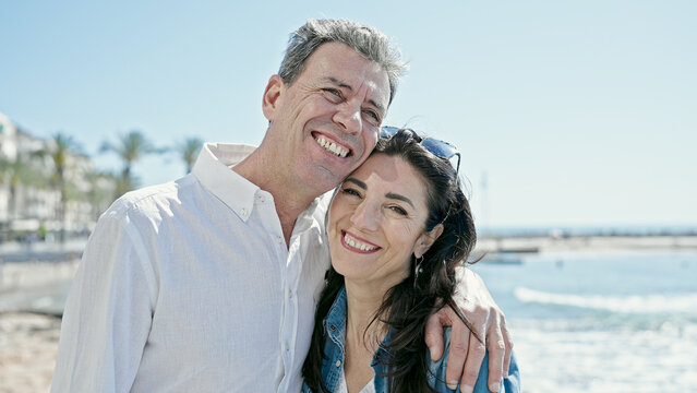 Senior man and woman couple smiling confident hugging each other at seaside