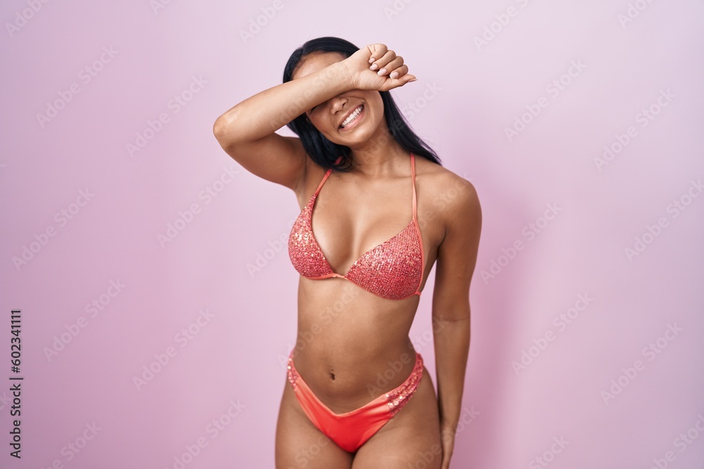 Sticker hispanic woman wearing bikini covering eyes with arm smiling cheerful and funny. blind concept.