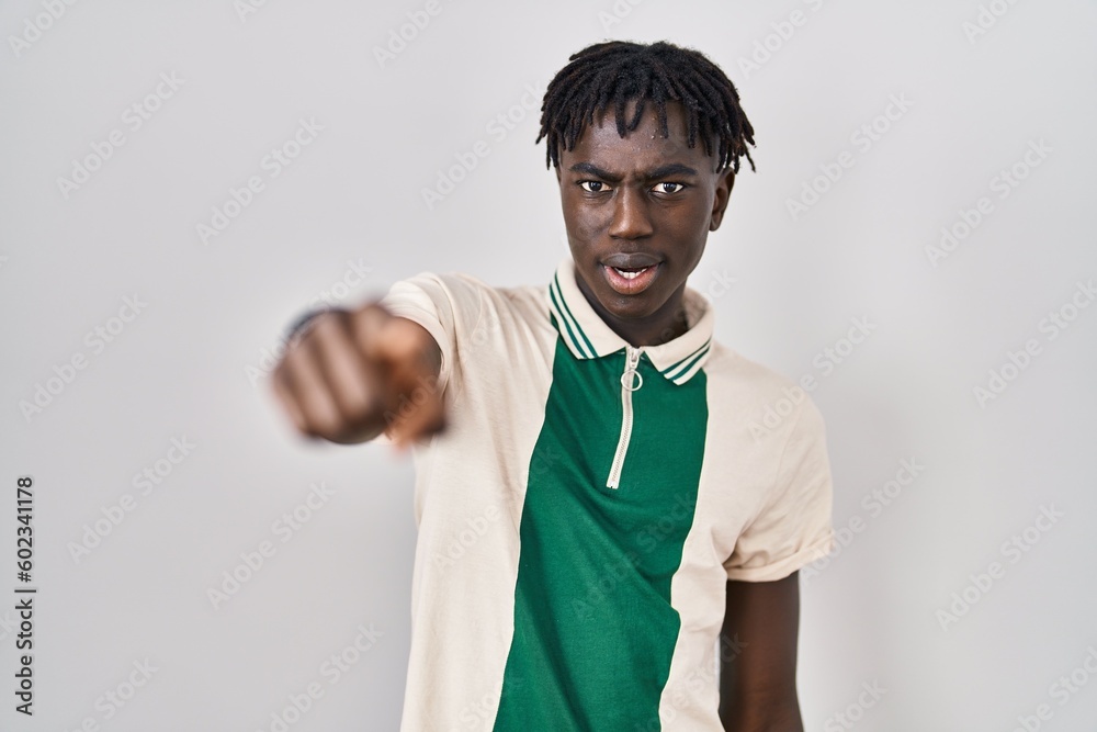 Sticker african man with dreadlocks standing over isolated background pointing displeased and frustrated to 