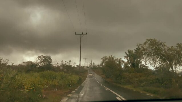 Moving right hand drive car by the Mauritius island inland road under the heavy rain. Inside the car driver view 4K video.