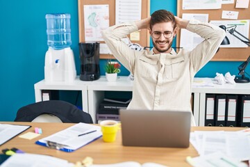 Young caucasian man business worker relaxed with hands on head at office