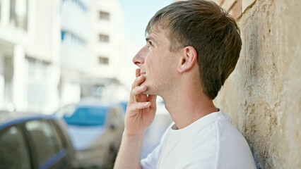 Young caucasian man looking to the side with serious expression at street