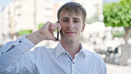 Young caucasian man smiling confident talking on smartphone at coffee shop terrace