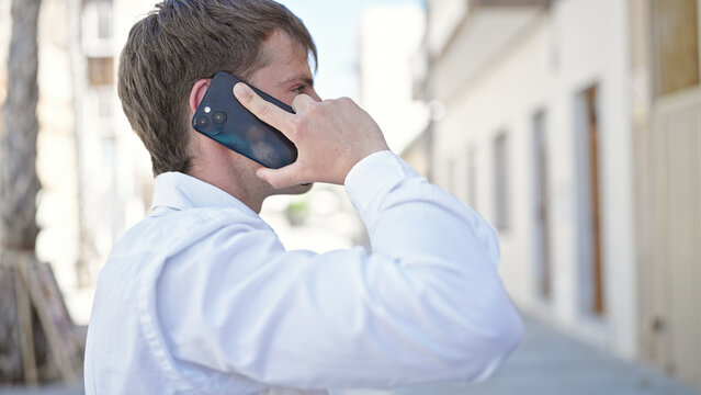 Young caucasian man talking on smartphone at street