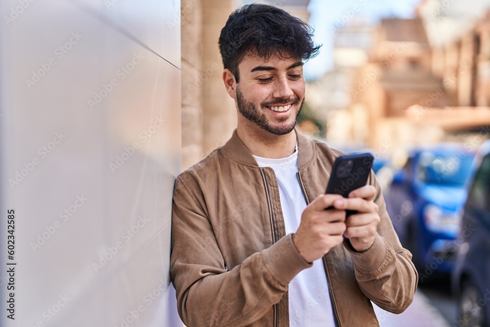 Sticker young hispanic man smiling confident using smartphone at street