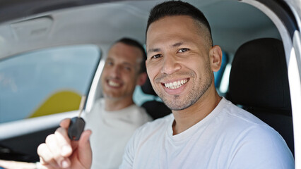Two men couple smiling confident holding key of new car at street