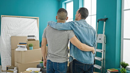 Two men hugging each other standing backwards at new home