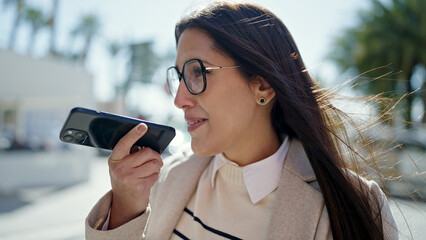Young beautiful hispanic woman sending voice message with smartphone at street