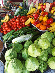 Still life. Food background with colorful ripe organic fruits and vegetable on shelf in local farmer market. Agribusiness. Cabbage, cucumbers, pepper, capsicum, tomatoes, greens, bananas, tangerines