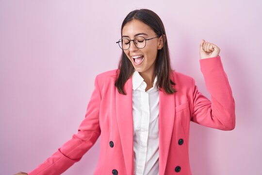 Young hispanic woman wearing business clothes and glasses dancing happy and cheerful, smiling moving casual and confident listening to music