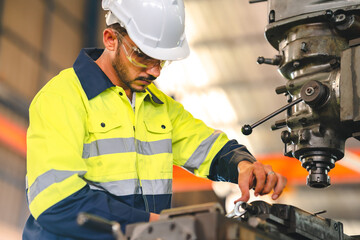 Production engineers in safety wear are assisting adjusting and maintaining CNC or factory machine,...