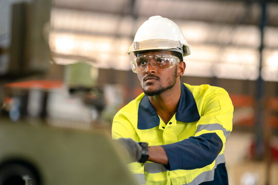 Production engineers in safety wear are assisting adjusting and maintaining CNC or factory machine, Male workers technician examining control the industrial tool, professional men at work in industry