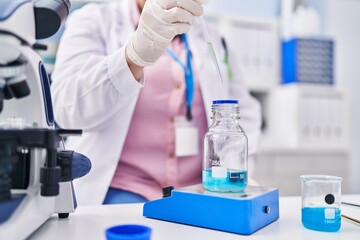 Fototapeta premium Young beautiful plus size woman scientist pouring liquid on test tube weighing liquid at laboratory