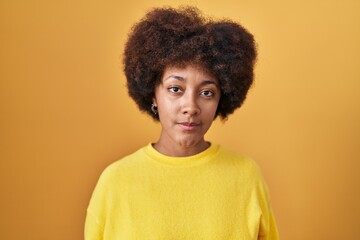 Obraz na płótnie Canvas Young african american woman standing over yellow background relaxed with serious expression on face. simple and natural looking at the camera.