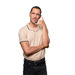 Hesitant young man making a gesture of calling with the hand