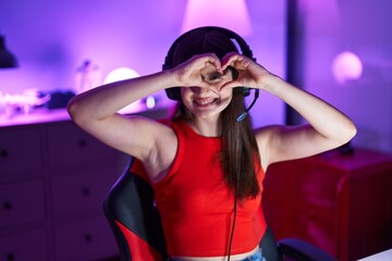 Obraz na płótnie Canvas Young caucasian woman streamer smiling confident doing heart symbol with hands at gaming room